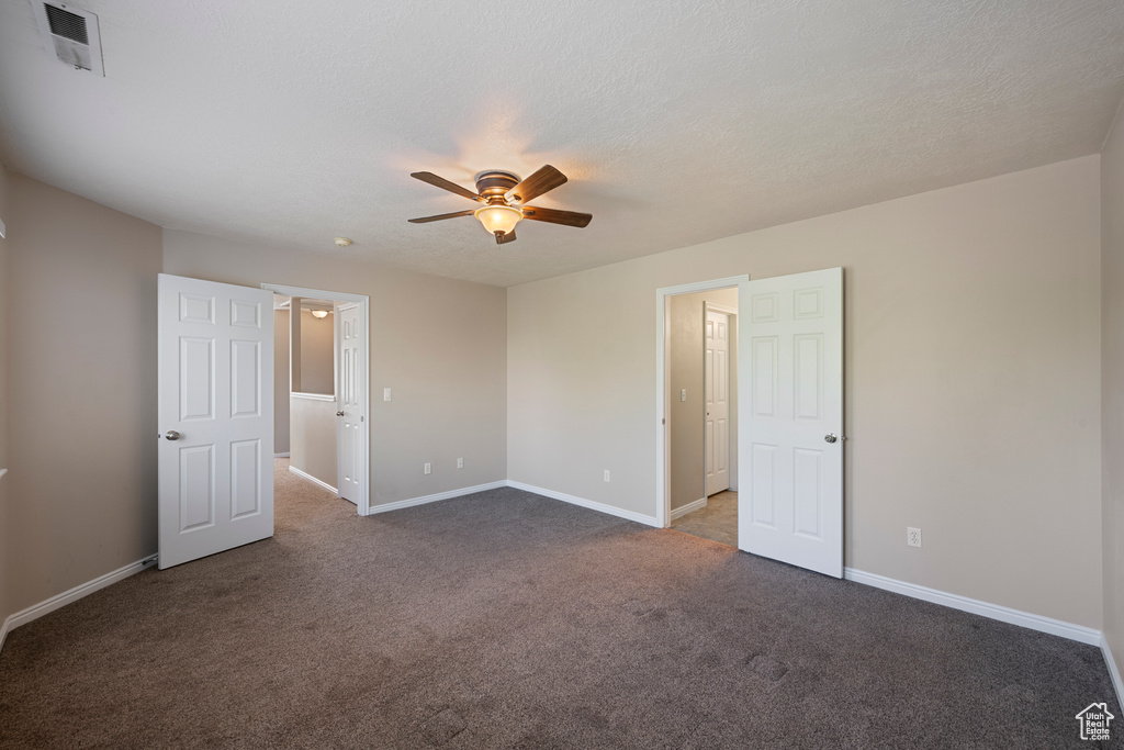 Unfurnished bedroom with baseboards, a ceiling fan, carpet flooring, and visible vents