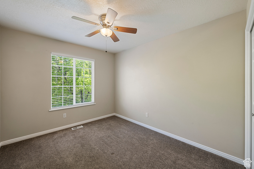 Unfurnished room with a textured ceiling, carpet, a ceiling fan, baseboards, and visible vents