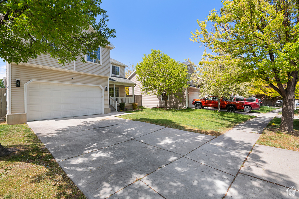 View of front facade with an attached garage, a front lawn, and driveway
