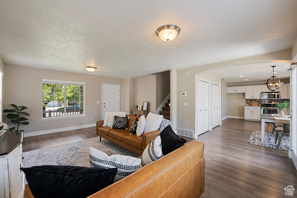 Living room featuring visible vents, arched walkways, stairs, and baseboards