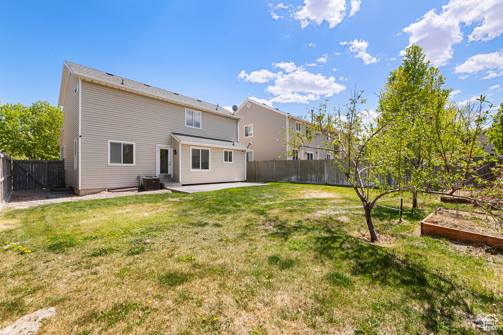 Back of house with a garden, a fenced backyard, a patio area, central air condition unit, and a yard