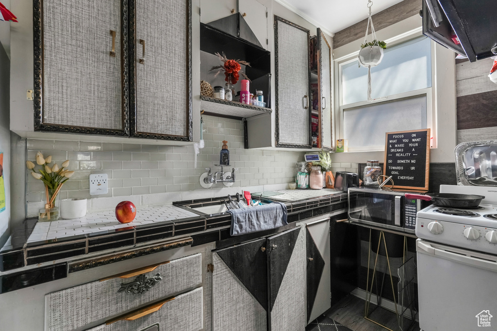 Kitchen featuring gas range gas stove, decorative backsplash, stainless steel microwave, and tile countertops