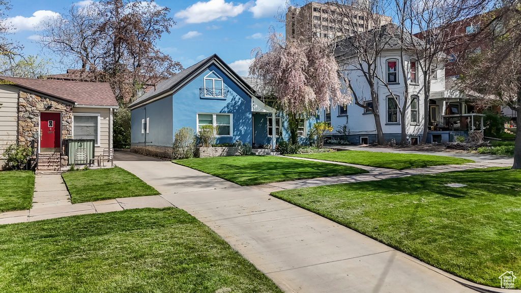 View of front of property with concrete driveway, stone siding, and a front yard