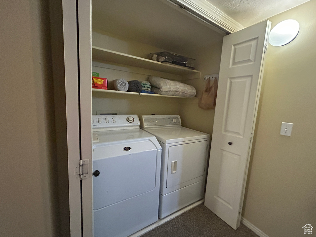 Laundry room featuring baseboards, laundry area, washer and clothes dryer, and dark colored carpet