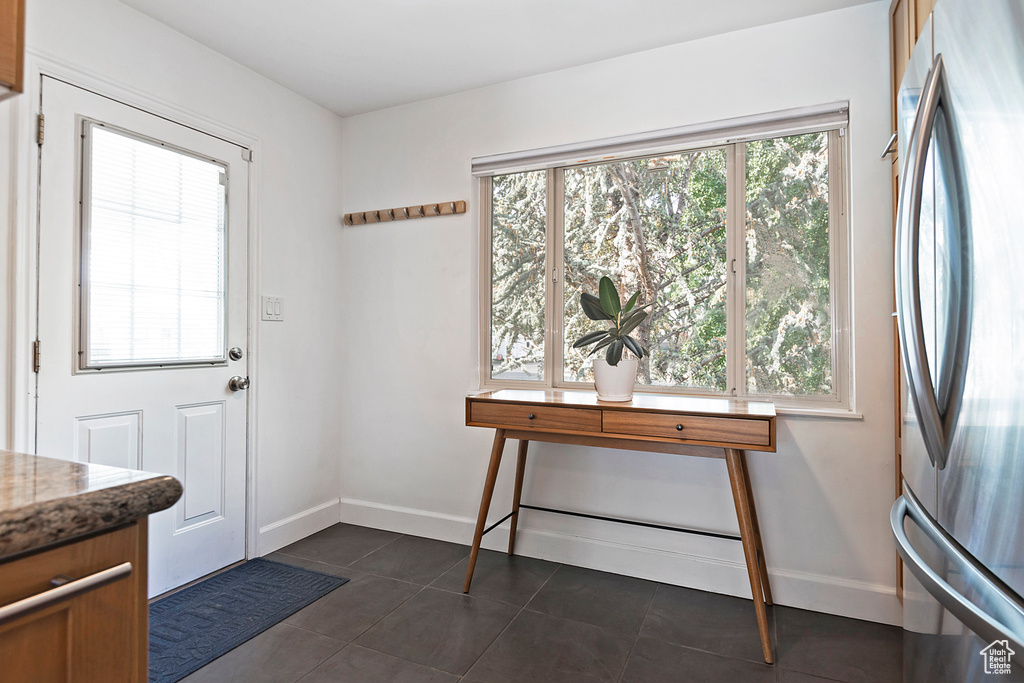 Doorway to outside featuring dark tile patterned floors and baseboards