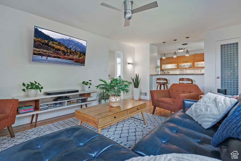Living area with baseboards, ceiling fan, wood finished floors, and visible vents