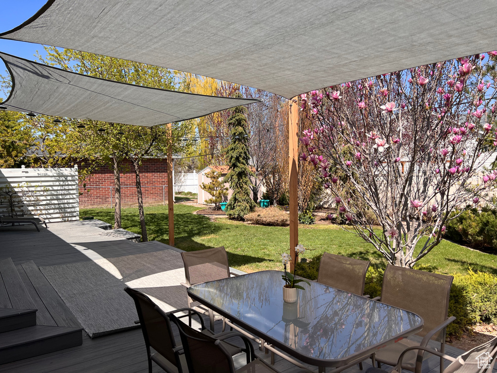 Wooden terrace with outdoor dining area, fence, and a yard
