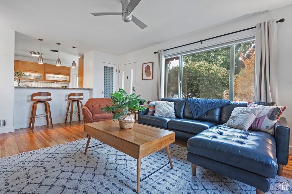 Living room with ceiling fan, visible vents, and light wood-type flooring