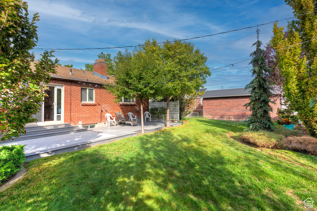 Back of house with a lawn, a chimney, a patio area, and brick siding