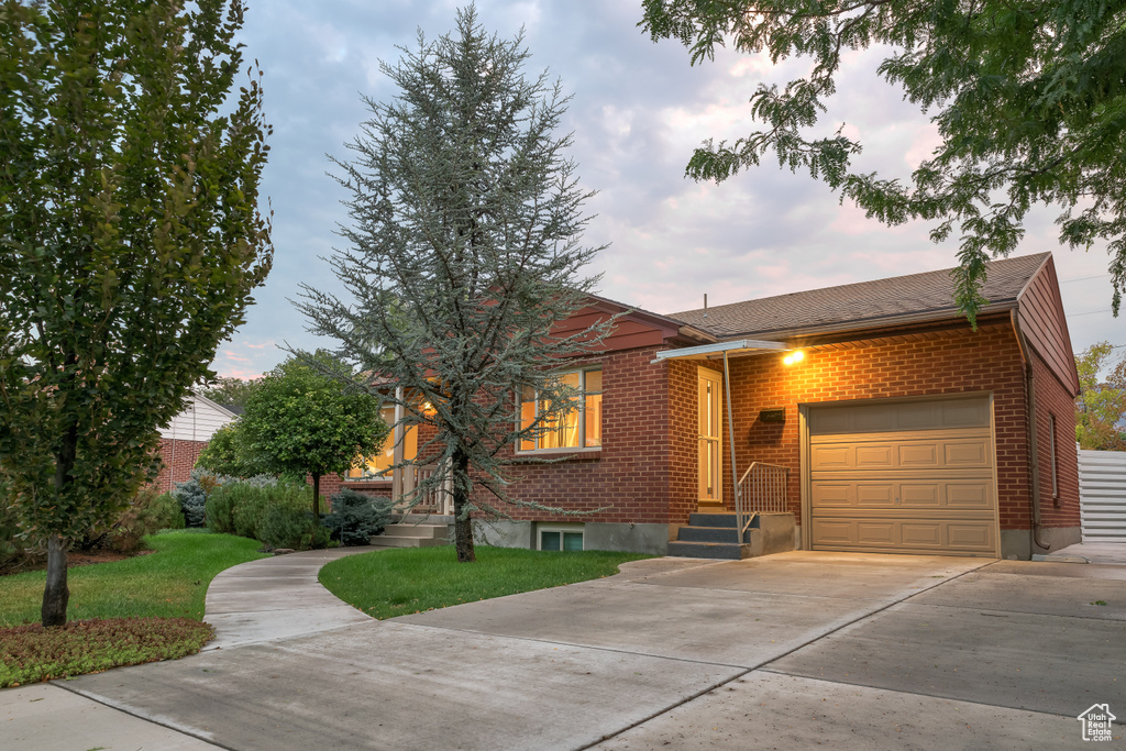 Ranch-style home featuring a garage, driveway, and brick siding