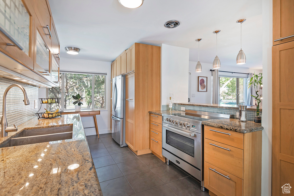 Kitchen featuring a sink, appliances with stainless steel finishes, decorative backsplash, and light stone countertops