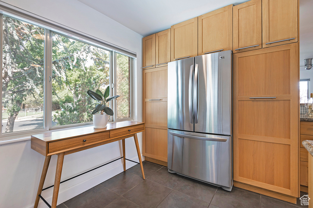 Kitchen with freestanding refrigerator, dark tile patterned floors, and light brown cabinets