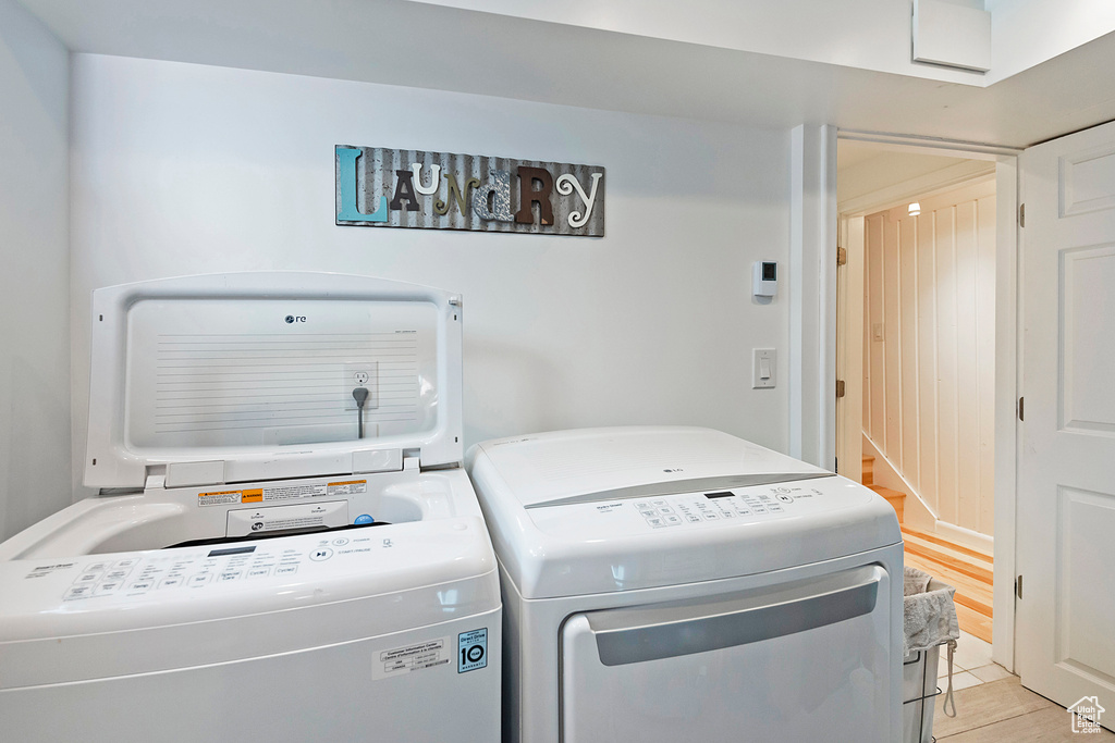 Clothes washing area featuring washer and dryer, laundry area, and light tile patterned floors