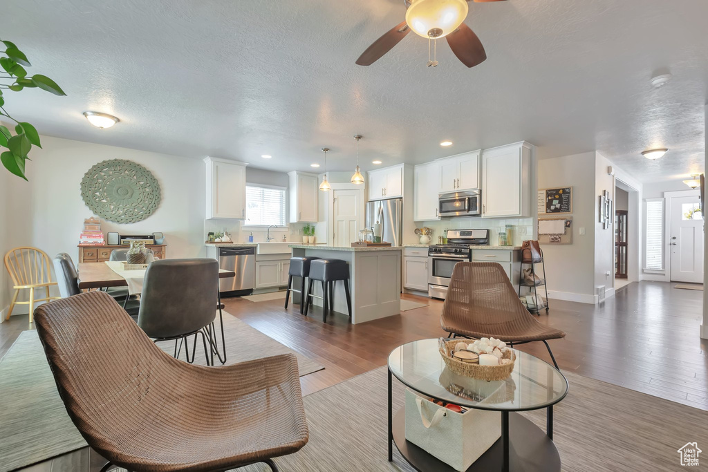 Living room featuring a textured ceiling, recessed lighting, and wood finished floors