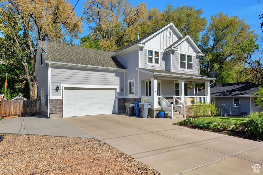 Traditional home featuring fence, covered porch, board and batten siding, an attached garage, and driveway