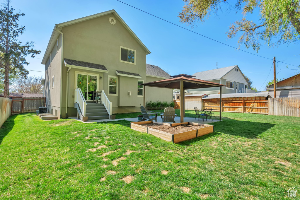 Back of house with a garden, a fenced backyard, stucco siding, a gazebo, and a yard