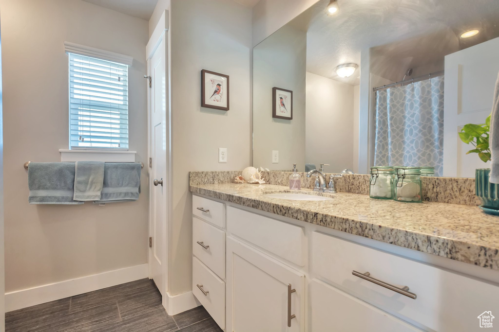 Bathroom featuring wood finished floors, baseboards, curtained shower, and vanity