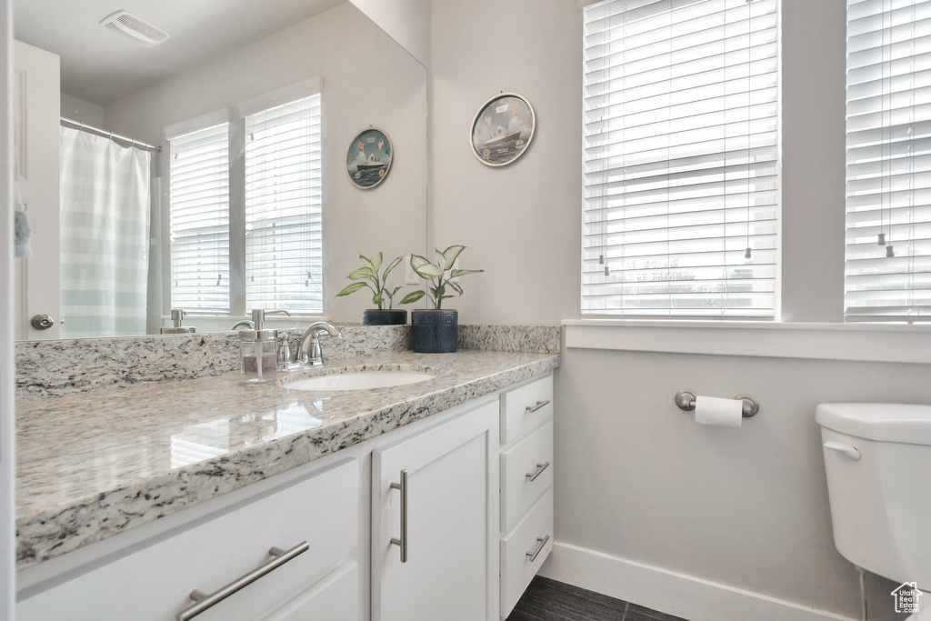 Full bath featuring vanity, baseboards, toilet, and visible vents