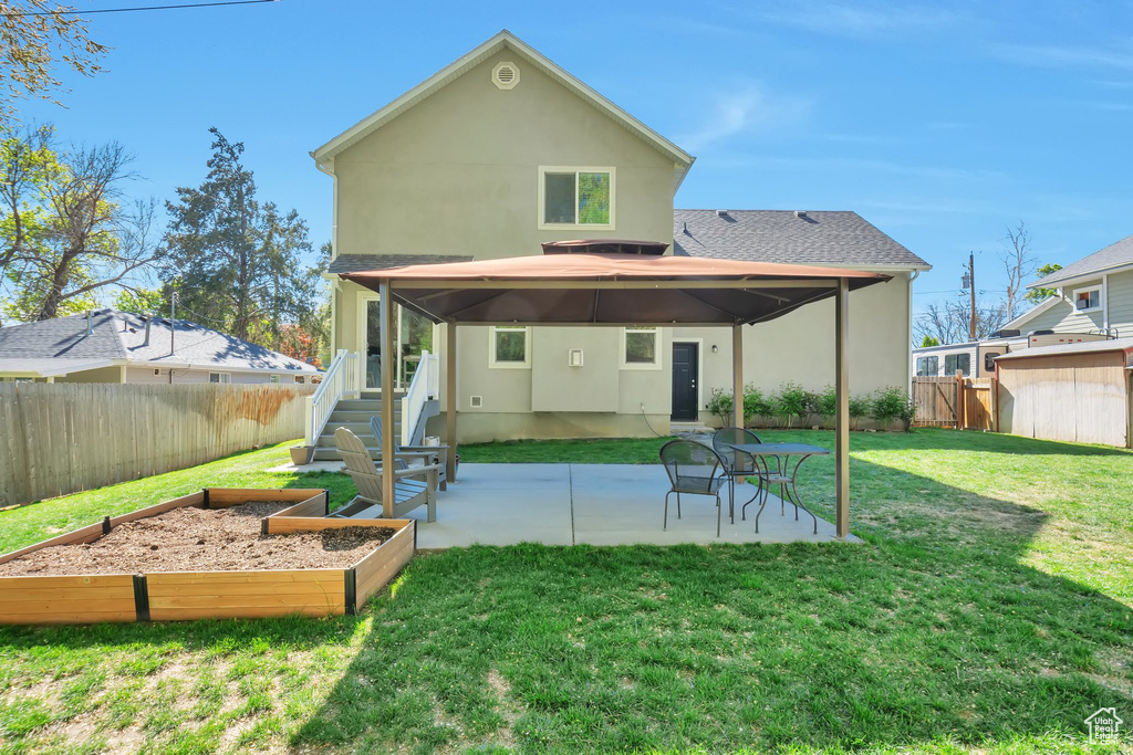 Back of house featuring a fenced backyard, a patio, stucco siding, and a garden