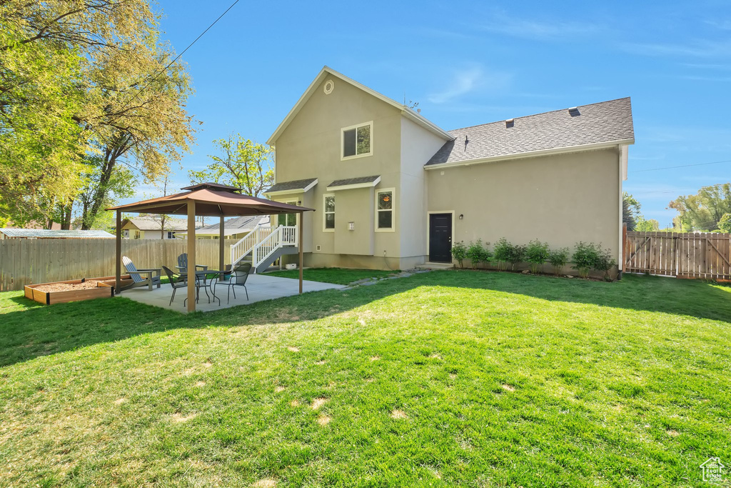 Back of house with a fenced backyard, stucco siding, a patio area, a gazebo, and a yard