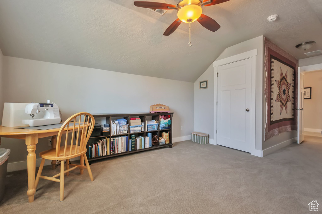 Carpeted home office featuring visible vents, a ceiling fan, baseboards, and vaulted ceiling