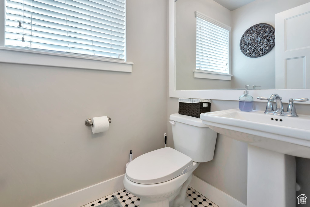 Half bath featuring a sink, baseboards, and toilet