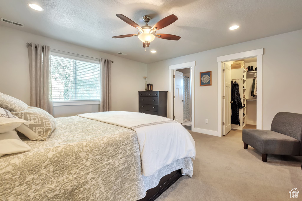 Bedroom with visible vents, recessed lighting, a walk in closet, and light colored carpet