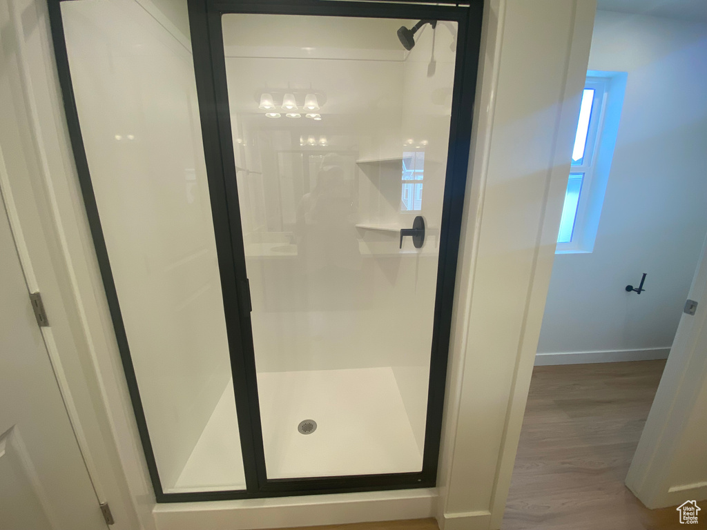 Full bathroom with baseboards, a shower stall, and wood finished floors