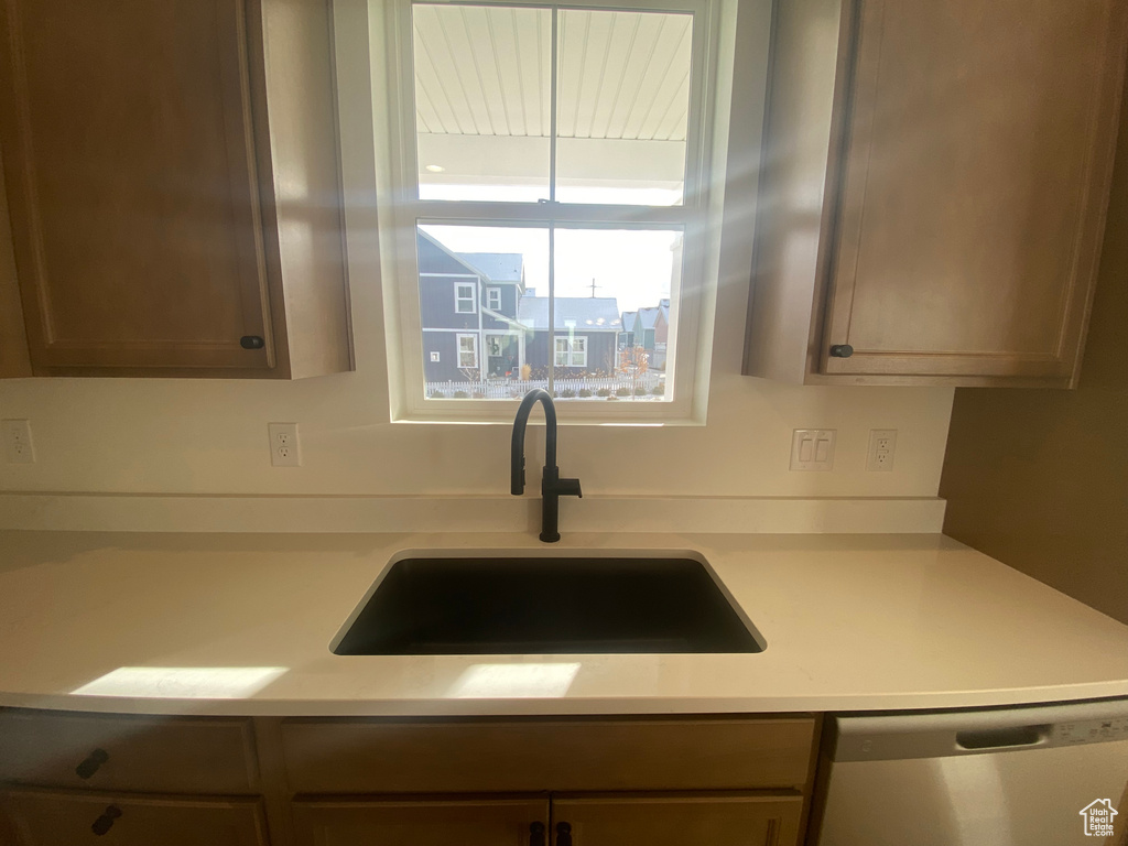 Kitchen with a sink, dishwasher, and light countertops
