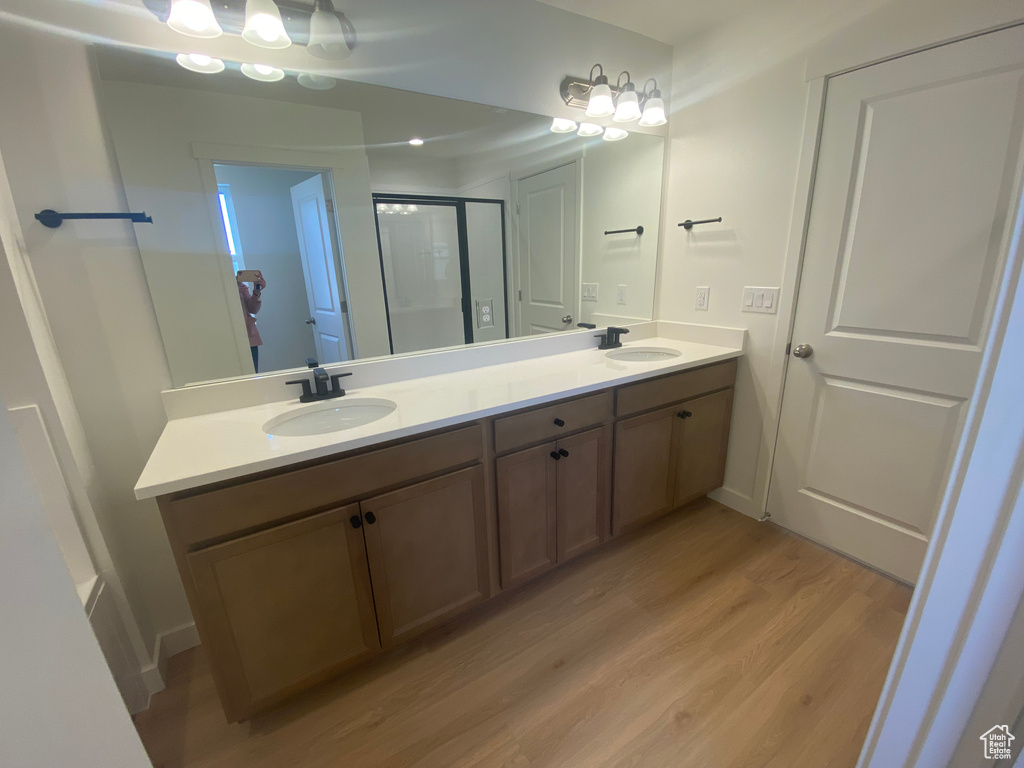 Bathroom featuring double vanity, a shower stall, a sink, and wood finished floors