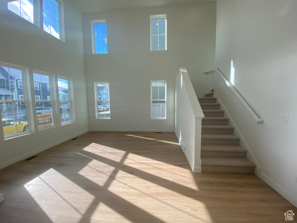 Unfurnished living room with a high ceiling, wood finished floors, and a healthy amount of sunlight