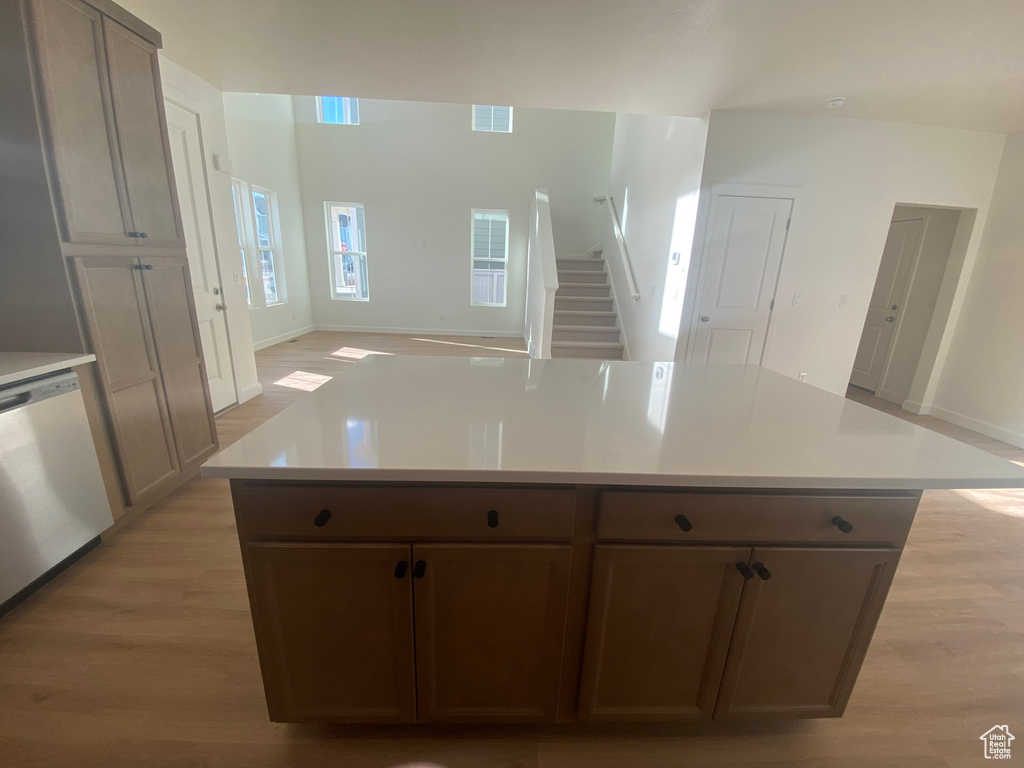 Kitchen with stainless steel dishwasher, open floor plan, light wood-style flooring, and visible vents