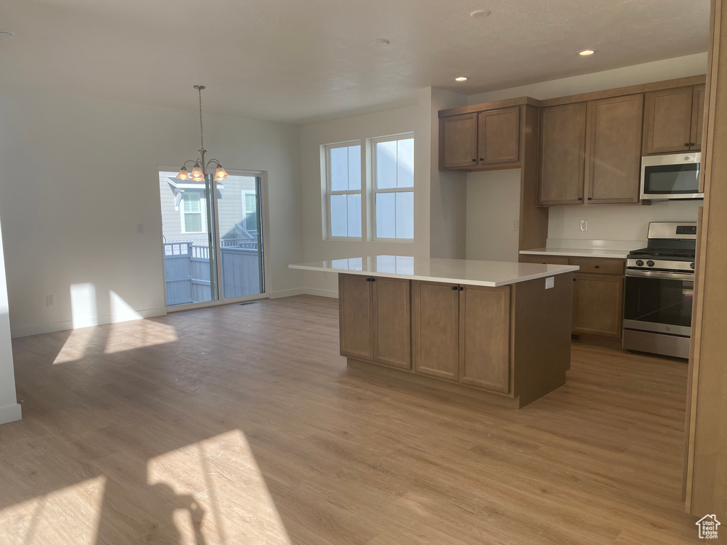 Kitchen featuring baseboards, a center island, recessed lighting, light wood finished floors, and stainless steel appliances