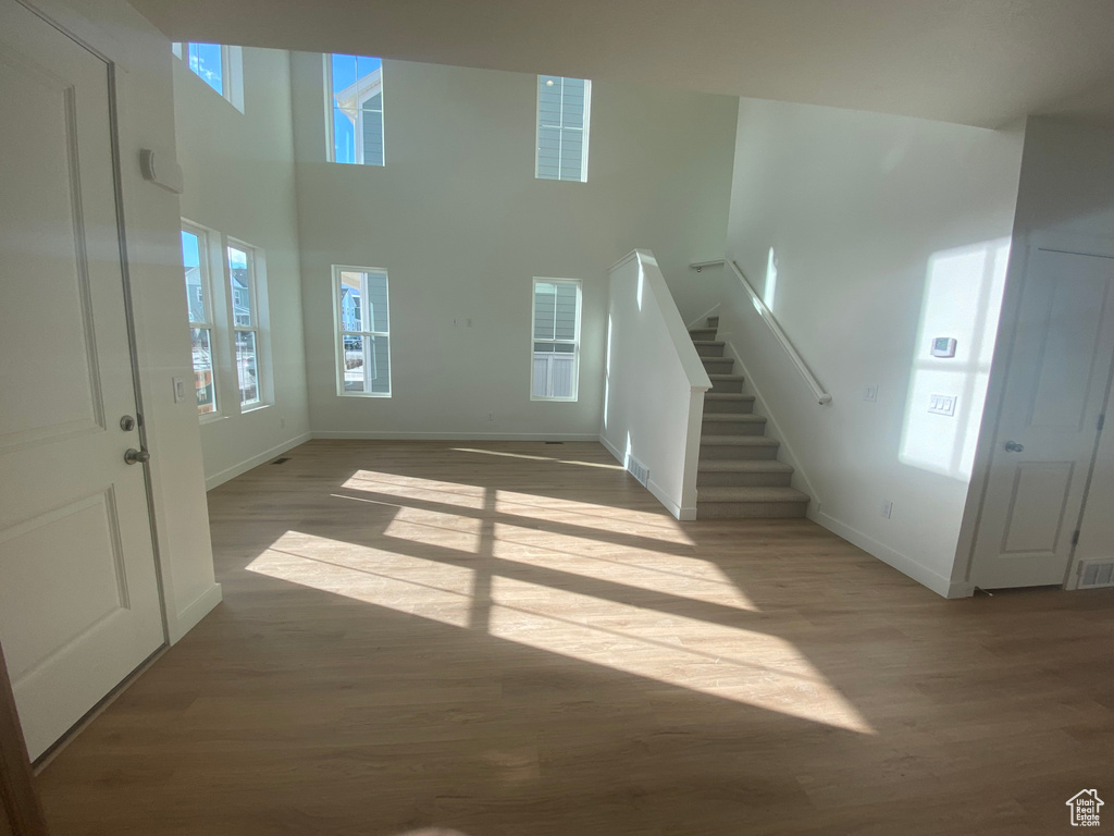 Unfurnished living room featuring baseboards, stairs, and wood finished floors