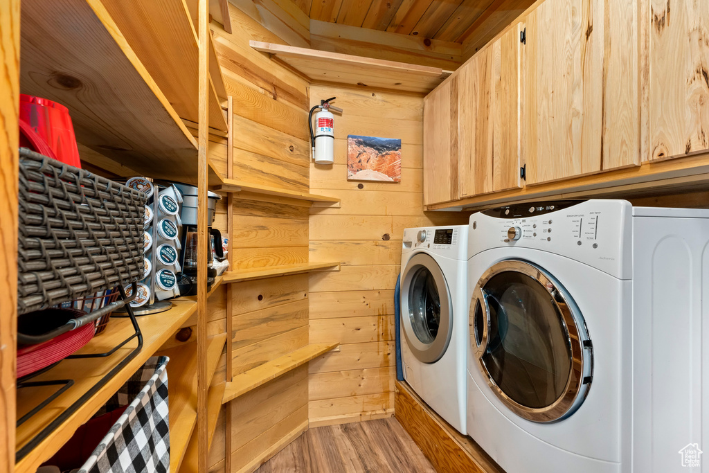 Laundry area with washer and clothes dryer, wood finished floors, and wooden walls