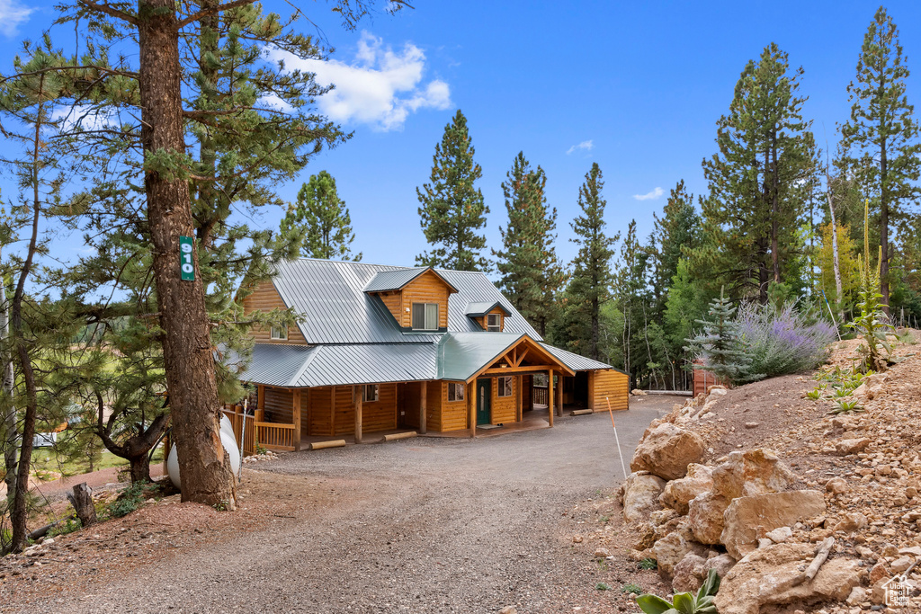 Chalet / cabin with covered porch, driveway, and metal roof