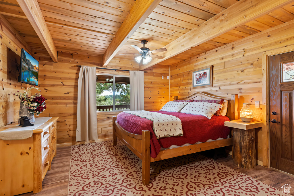 Bedroom with wooden walls, light wood-style floors, access to exterior, beamed ceiling, and wood ceiling