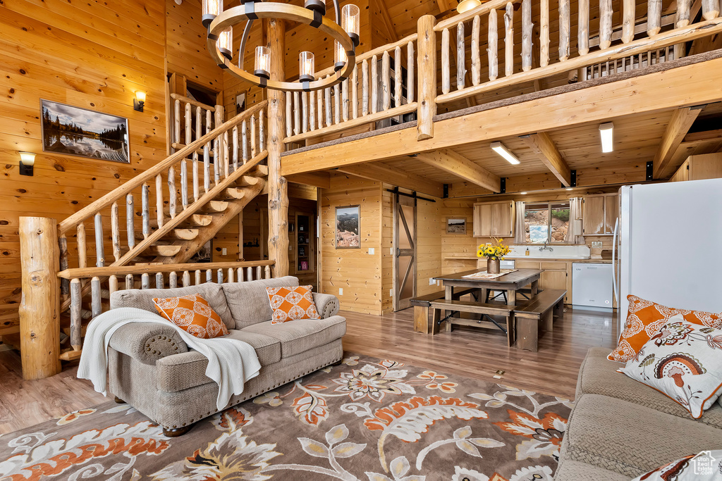 Living room featuring stairway, beam ceiling, wood walls, and wood finished floors