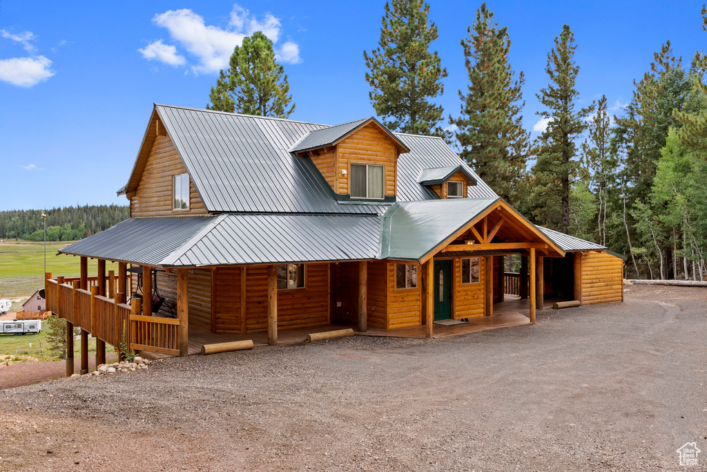 View of front facade featuring covered porch, log veneer siding, and metal roof