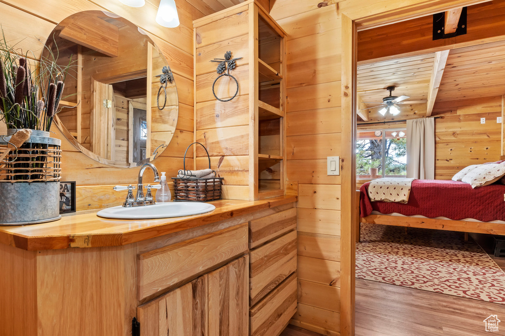 Ensuite bathroom featuring wooden walls, ceiling fan, vanity, wood finished floors, and wood ceiling
