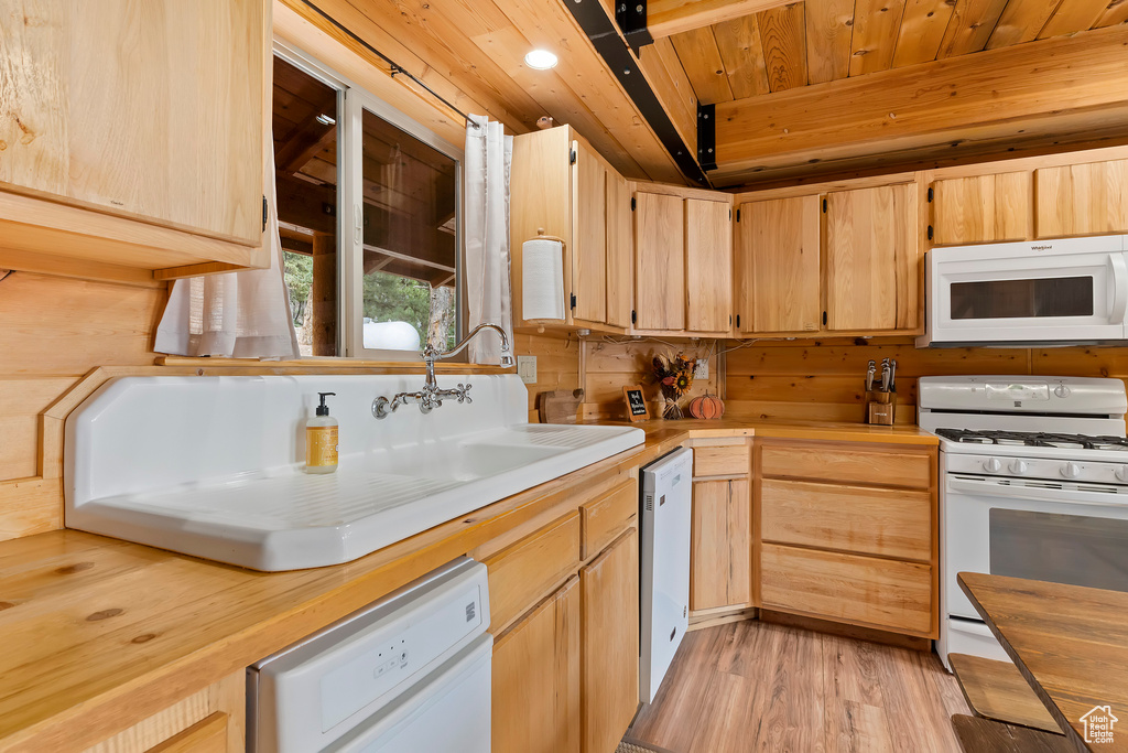 Kitchen with light brown cabinets, white appliances, light wood-style flooring, wooden ceiling, and butcher block counters
