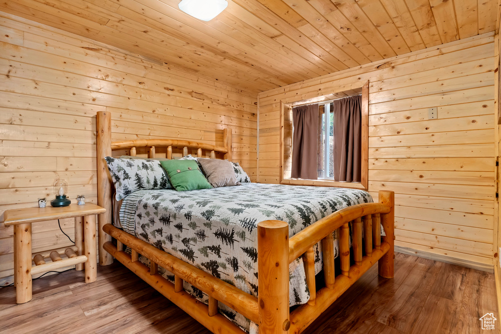 Bedroom with wood-type flooring, wood ceiling, and wooden walls