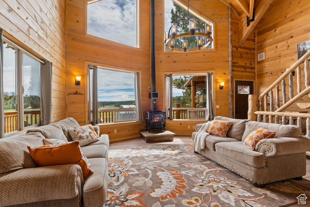 Living area featuring a wood stove, stairs, wood finished floors, wooden walls, and high vaulted ceiling