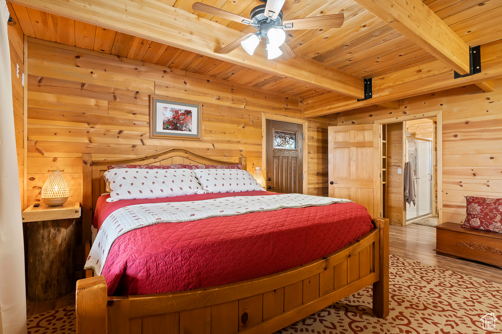 Bedroom with wooden walls, wood ceiling, beamed ceiling, and wood finished floors