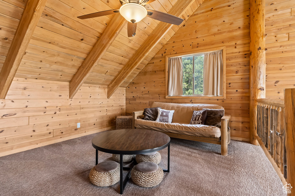 Living area featuring wooden walls, wooden ceiling, lofted ceiling with beams, and carpet floors