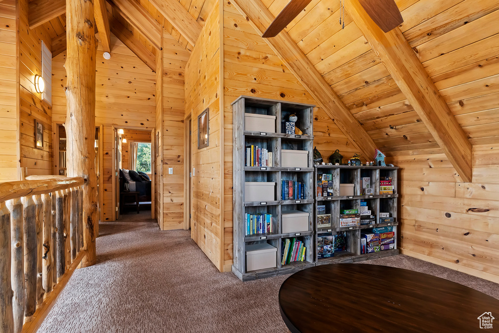 Corridor featuring wood walls, vaulted ceiling with beams, and carpet
