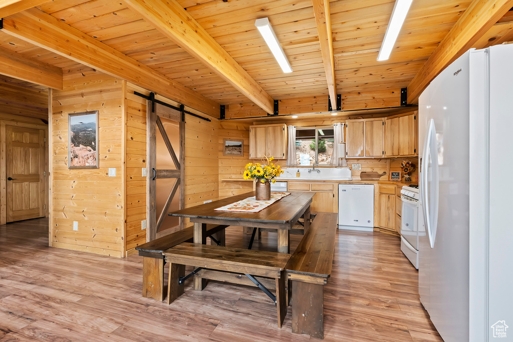 Kitchen featuring light countertops, beam ceiling, white appliances, and a barn door