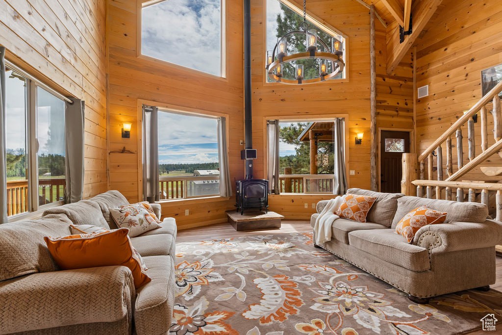 Living area featuring high vaulted ceiling, wood walls, wood finished floors, and a wood stove