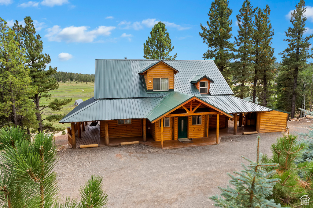 Rustic home featuring a porch, driveway, metal roof, and faux log siding