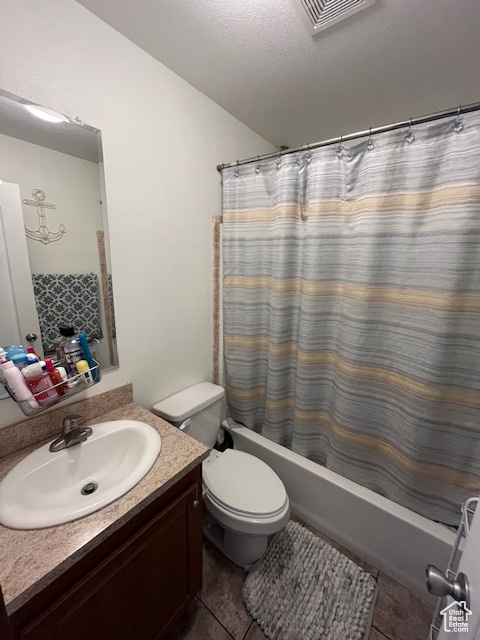 Full bath with tile patterned flooring, vanity, shower / bath combo with shower curtain, toilet, and visible vents